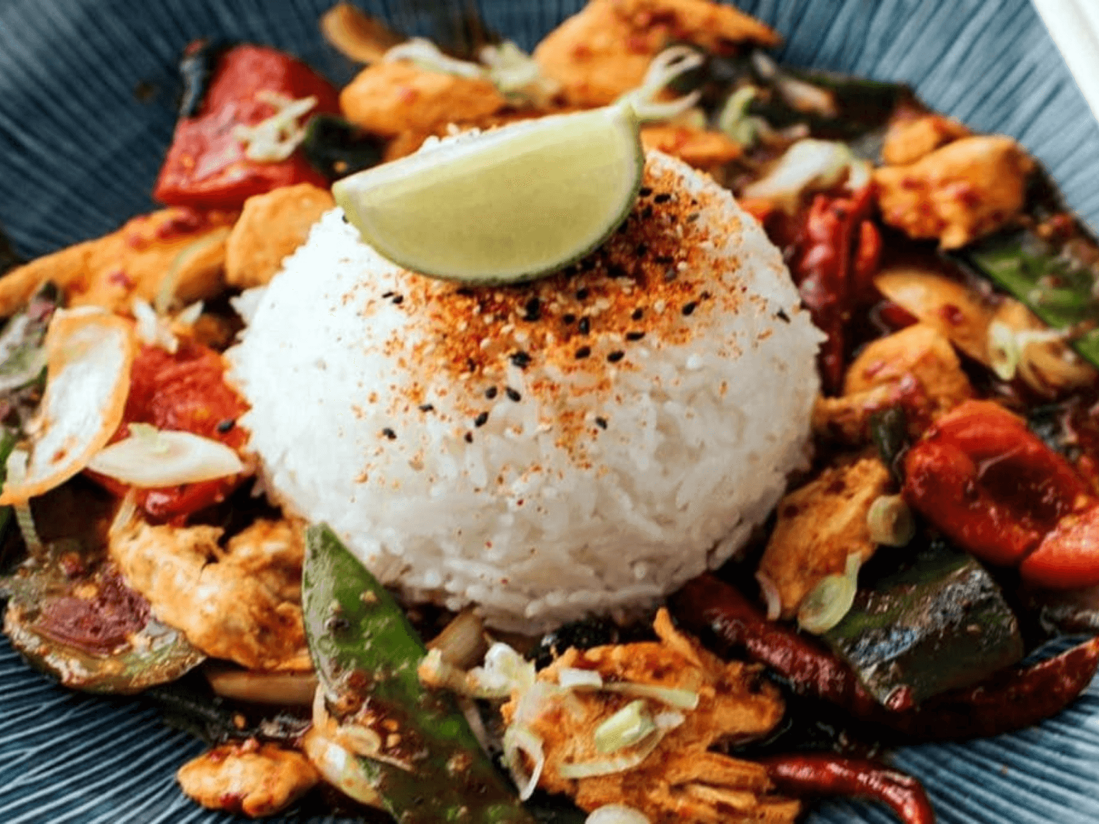 Wagamama chicken firecracker curry served with white rice, lime wedge, and vegetables.